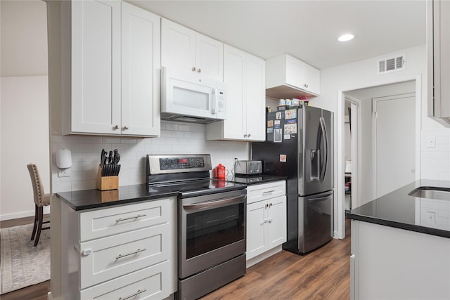 kitchen with stainless steel appliances, dark countertops, dark wood finished floors, tasteful backsplash, and recessed lighting