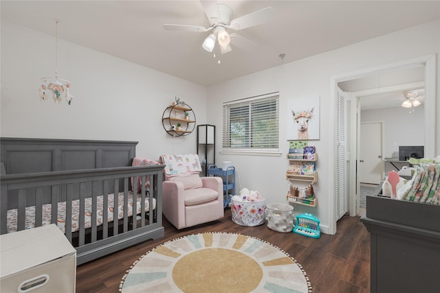 bedroom featuring wood finished floors, a crib, ceiling fan, and baseboards