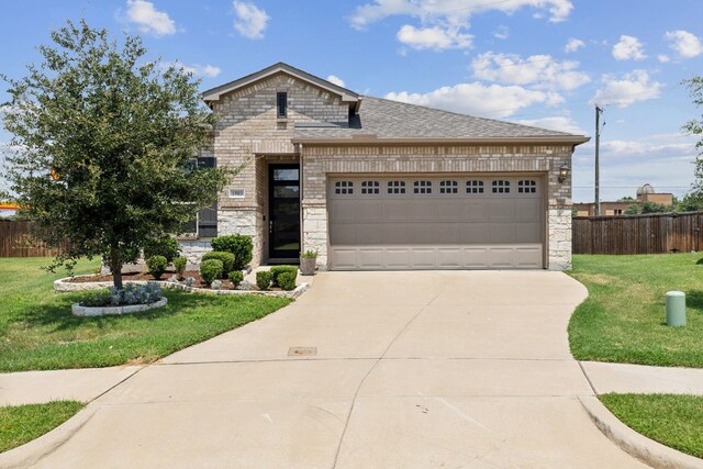 french country home featuring fence, a front yard, driveway, and stone siding