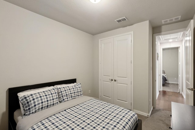 carpeted bedroom featuring baseboards, visible vents, attic access, and a closet