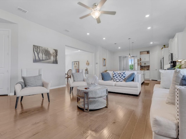 living room with a ceiling fan, visible vents, light wood-type flooring, baseboards, and recessed lighting
