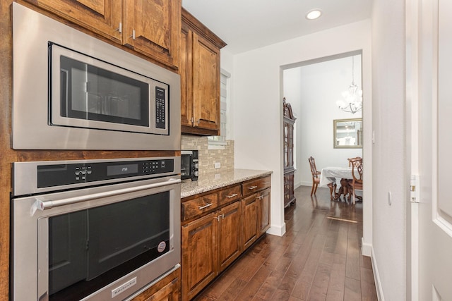 760 Durham St, Allen, TX 75013 - kitchen featuring stainless steel appliances, dark wood-type flooring, a chandelier, tasteful backsplash, and baseboards