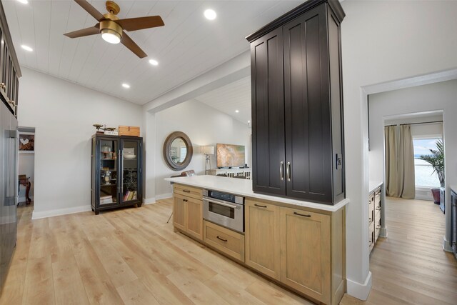 kitchen featuring vaulted ceiling, oven, light wood-style floors, ceiling fan, and light countertops