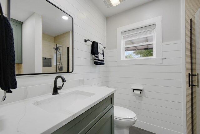 full bath featuring wooden walls, vanity, a shower stall, and toilet