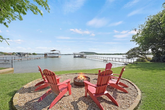 view of yard featuring a fire pit, a water view, and a dock