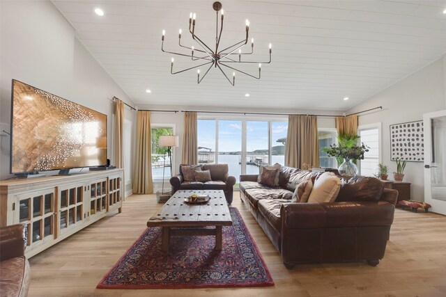 living area featuring vaulted ceiling, a healthy amount of sunlight, a chandelier, and wood finished floors