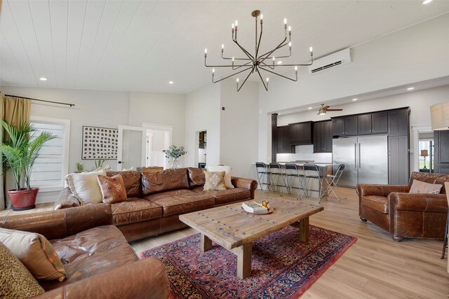 living room featuring recessed lighting, a wall mounted air conditioner, light wood-style flooring, high vaulted ceiling, and a notable chandelier
