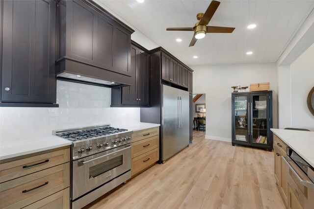 kitchen with tasteful backsplash, light wood-style floors, high end appliances, ceiling fan, and light countertops