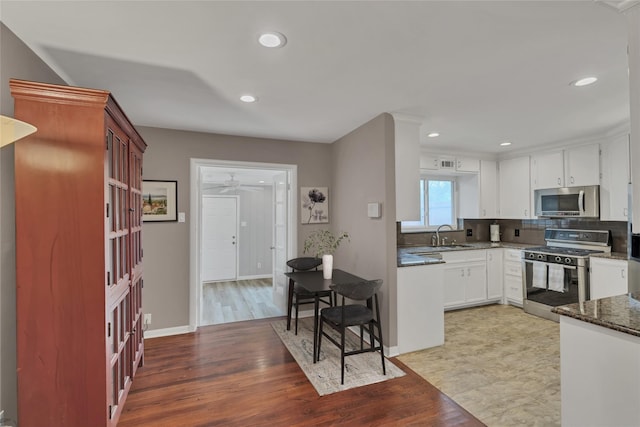 kitchen with gas range oven, stainless steel microwave, white cabinetry, and recessed lighting