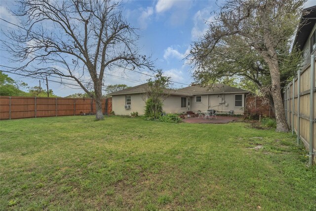 rear view of house with a yard, a fenced backyard, and a patio