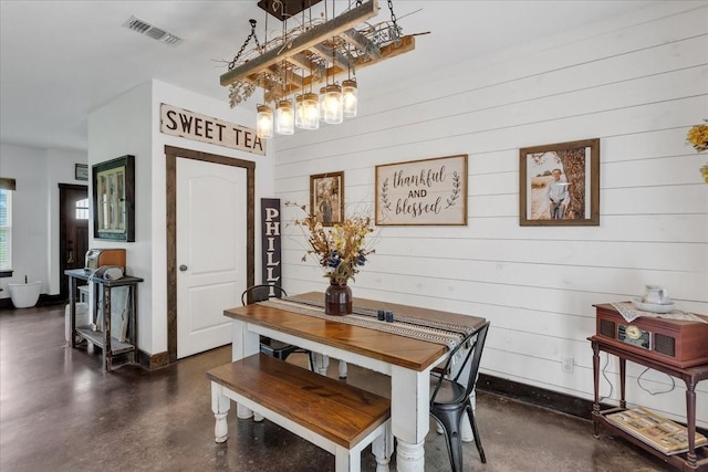 4024 County Road 2610, Bonham, TX 75418 - dining room with finished concrete floors, a chandelier, wooden walls, and baseboards