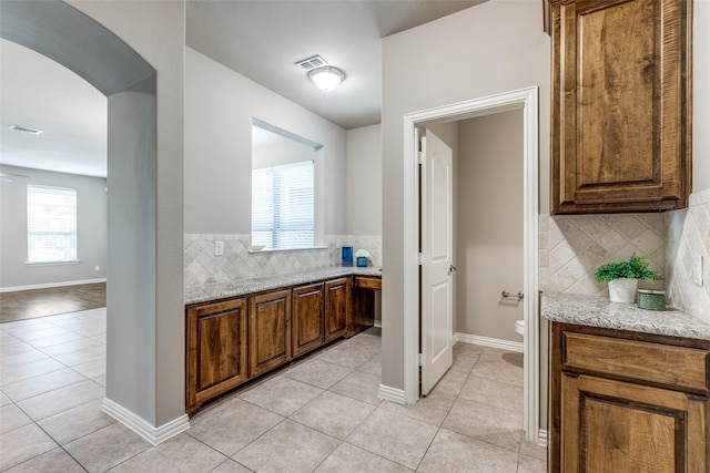 4301 Blackjack Oak Dr, Mckinney, TX 75070 - bar with arched walkways, backsplash, light tile patterned floors, and baseboards