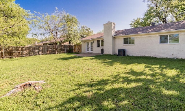 view of yard with french doors, a fenced backyard, and central AC unit