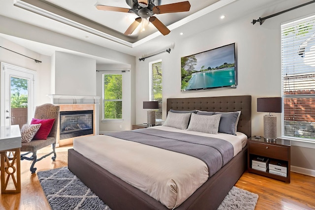 1406 Jacob Ave, Keller, TX 76248 - bedroom with a fireplace, a tray ceiling, a ceiling fan, recessed lighting, and wood finished floors