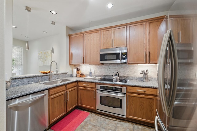 kitchen featuring light stone counters, appliances with stainless steel finishes, tasteful backsplash, and a sink
