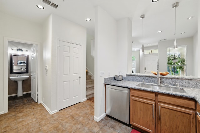 kitchen featuring stainless steel dishwasher, a sink, visible vents, light stone countertops, and brown cabinetry