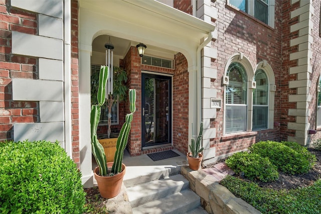 entrance to property with brick siding and a porch