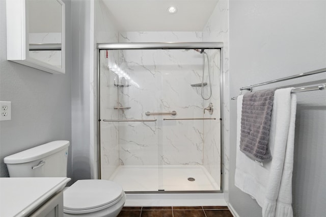 bathroom featuring tile patterned flooring, toilet, vanity, and a marble finish shower