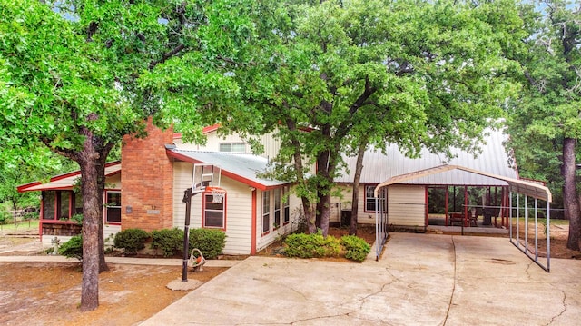 view of front of property featuring concrete driveway, a carport, and metal roof