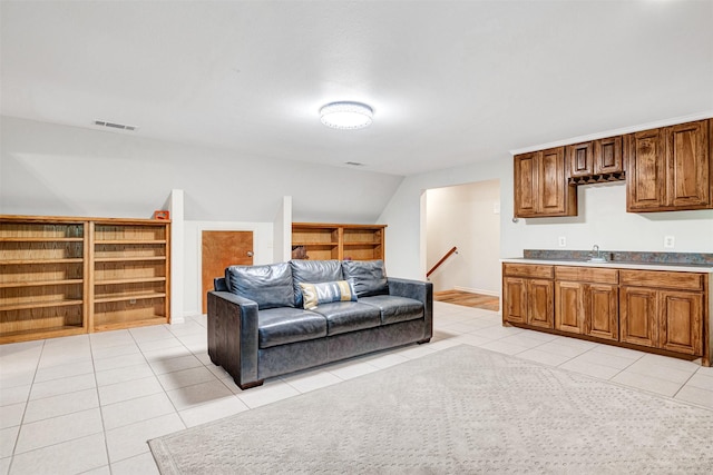 living area with visible vents, light tile patterned floors, and vaulted ceiling