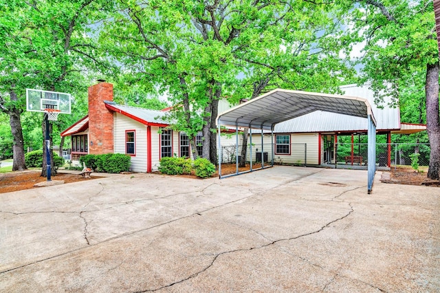 view of home's community with a carport, concrete driveway, and fence