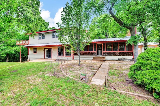 rear view of property featuring a yard, metal roof, a patio area, and a sunroom