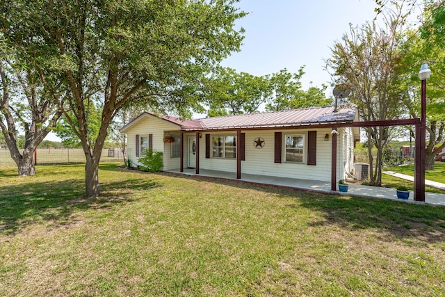 single story home featuring cooling unit, metal roof, and a front yard