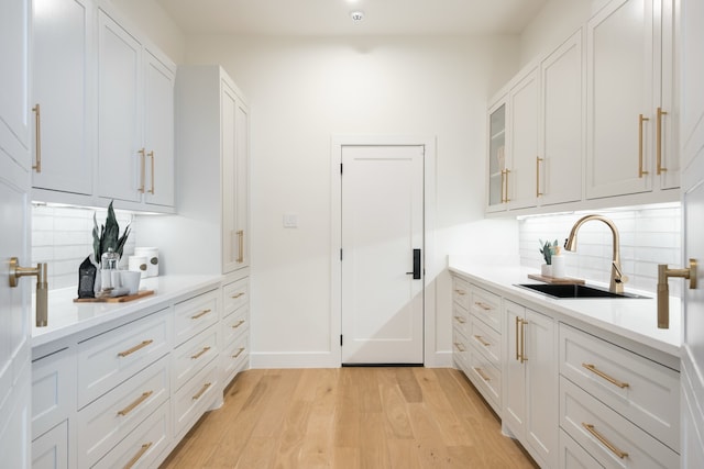 4147 Deep Valley Dr, Dallas, TX 75244 - kitchen featuring white cabinets, a sink, light wood finished floors, light countertops, and backsplash