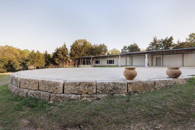 view of front facade featuring concrete driveway, an outdoor structure, a chimney, and a garage