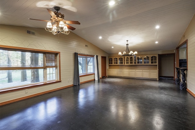 interior space featuring lofted ceiling, wooden walls, visible vents, baseboards, and ceiling fan with notable chandelier