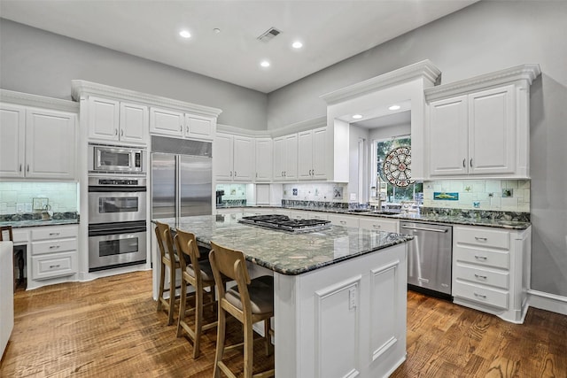 10040 Little Horn Cir, Frisco, TX 75035 - kitchen with built in appliances, a center island, white cabinets, dark stone countertops, and decorative backsplash