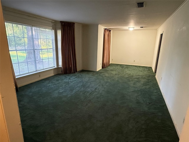 unfurnished room with visible vents, baseboards, and dark colored carpet
