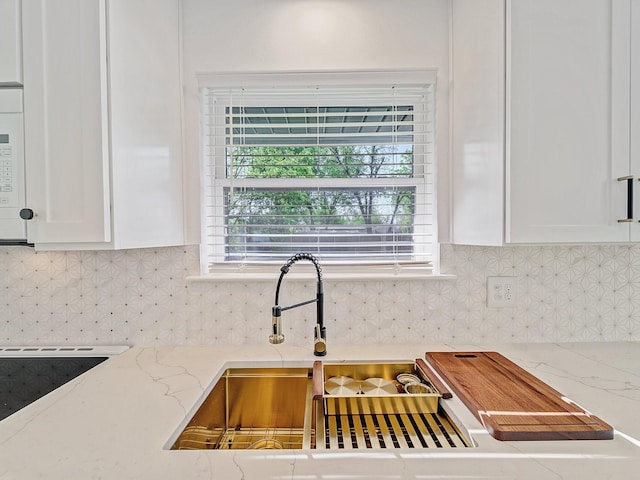 kitchen with white cabinets, backsplash, and light stone counters