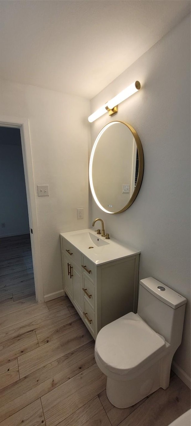 bathroom featuring toilet, wood finished floors, vanity, and baseboards