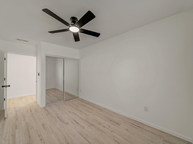unfurnished bedroom featuring visible vents, baseboards, a closet, ceiling fan, and wood finished floors
