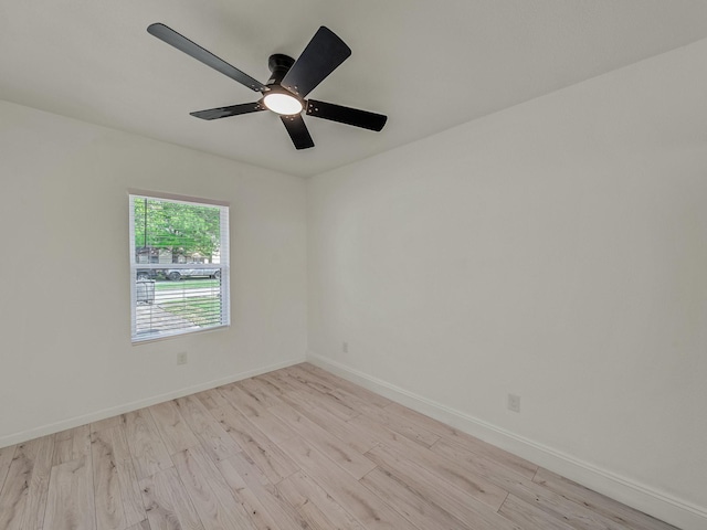 spare room with baseboards, light wood finished floors, and a ceiling fan