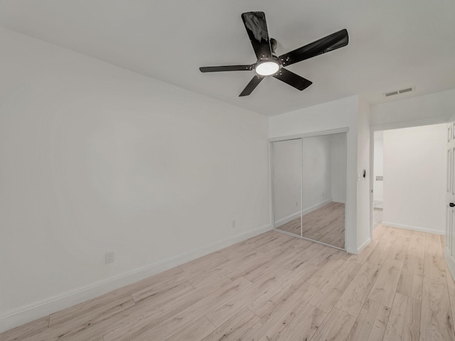 unfurnished bedroom with ceiling fan, light wood-type flooring, a closet, visible vents, and baseboards
