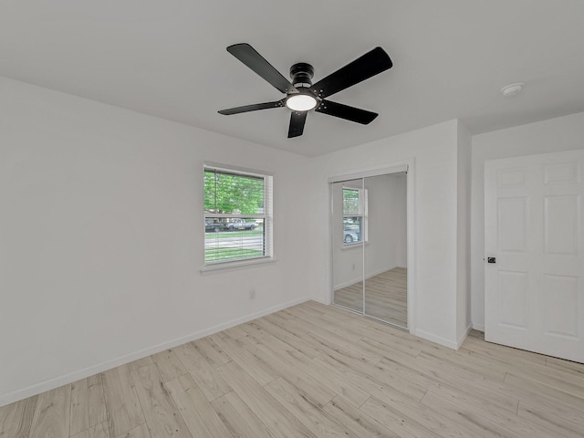 unfurnished bedroom with light wood-style flooring, a closet, baseboards, and a ceiling fan