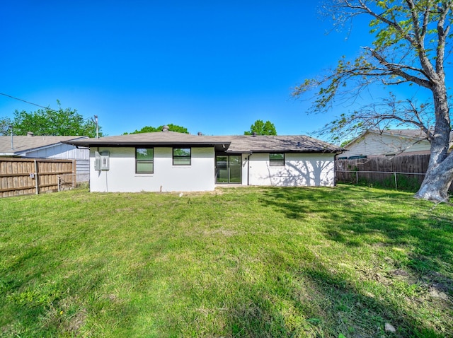 rear view of property featuring a yard, a fenced backyard, and stucco siding