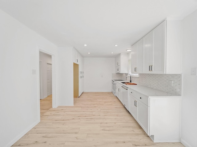 kitchen with baseboards, dishwasher, a sink, light wood-type flooring, and backsplash