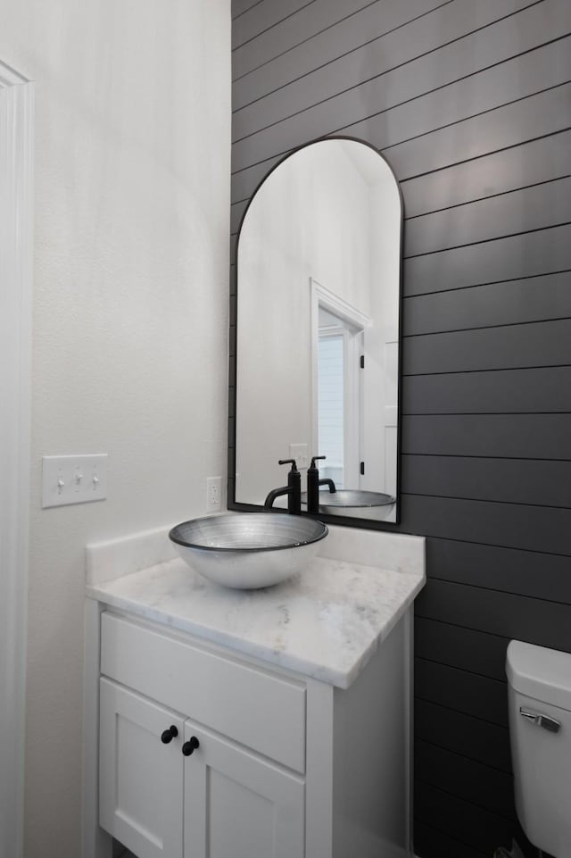 109 Post Oak Cv, Sunset, TX 76270 - bathroom featuring toilet, wood walls, and vanity