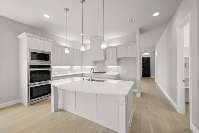 1616 Olympia Ave, Corinth, TX 76208 - kitchen featuring white cabinets, light wood-type flooring, backsplash, a kitchen island with sink, and recessed lighting