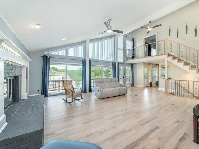 living room featuring ceiling fan, high vaulted ceiling, a brick fireplace, and baseboards