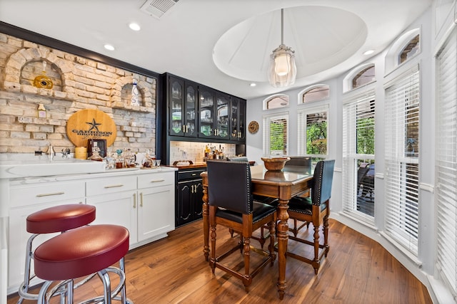 dining space featuring recessed lighting, indoor wet bar, visible vents, and wood finished floors