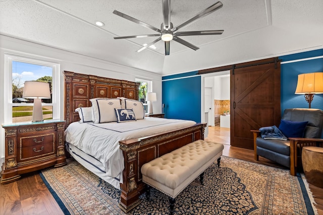 bedroom featuring multiple windows, a textured ceiling, and wood finished floors