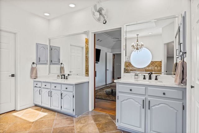 full bathroom featuring a chandelier, two vanities, a sink, and backsplash