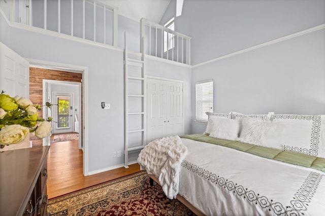 bedroom with a high ceiling, wood finished floors, baseboards, and multiple windows