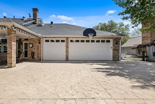 view of front of house featuring a garage, a shingled roof, decorative driveway, and a gate