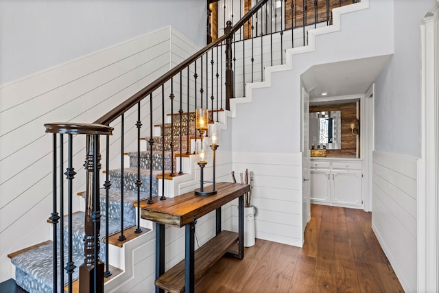 stairway featuring wood walls, wainscoting, and wood finished floors