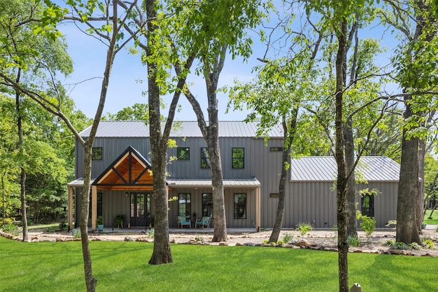 rear view of house with board and batten siding, a standing seam roof, metal roof, and a lawn